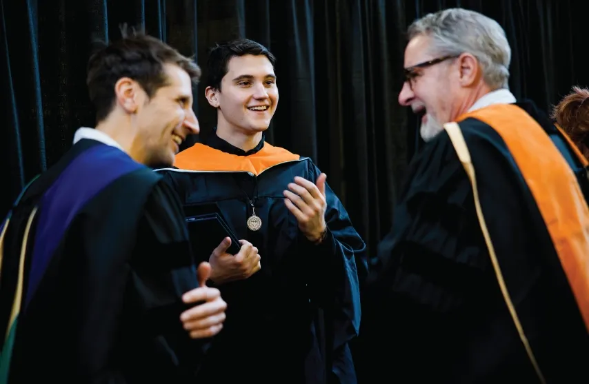 Three people smiling in a candid commencement picture.